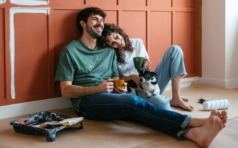 Couple sitting with dog resting after painting their home
