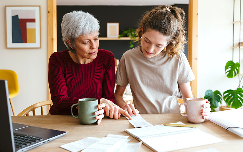 Mother and daughter looking at financial documents at table