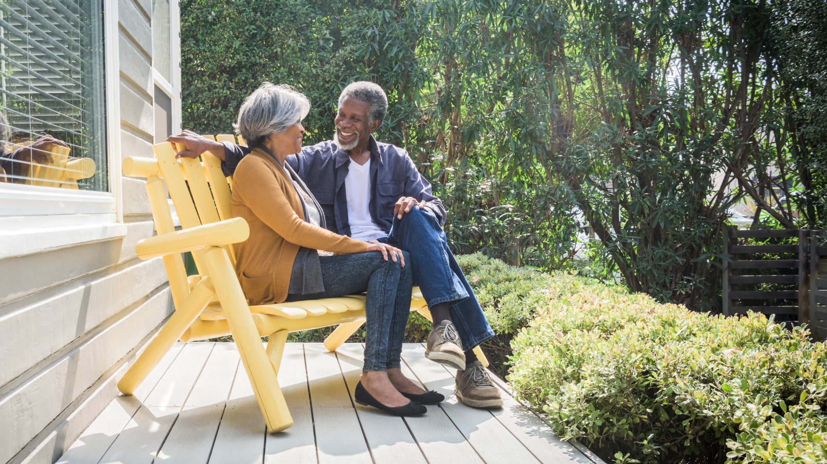 senior couple sitting on their porch relaxing outside their home