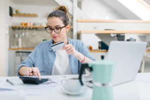 Woman holding credit card while working on her calculator