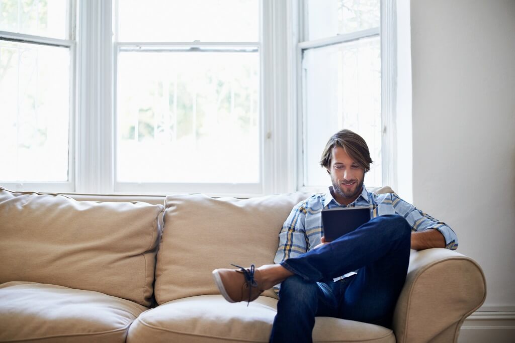 man sitting on couch checking his credit score
