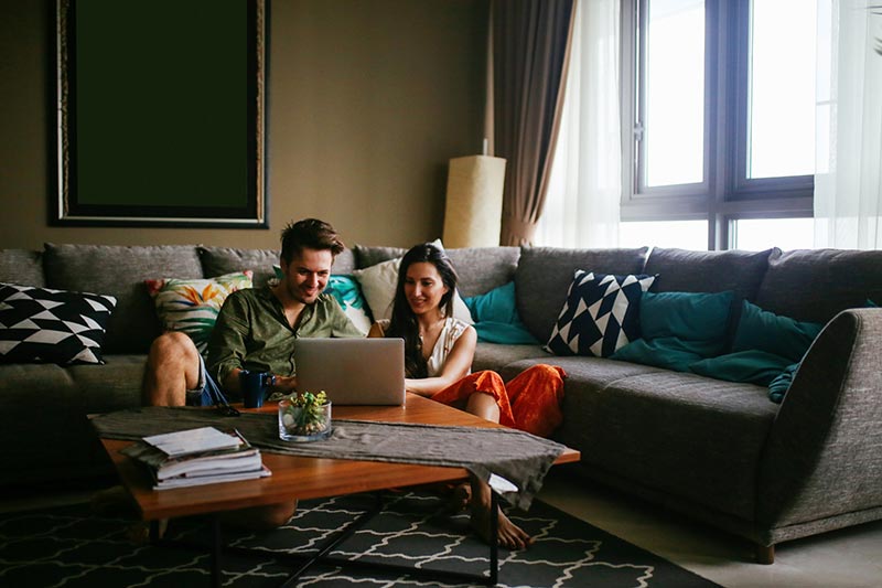 young couple sitting at coffee table looking at laptop