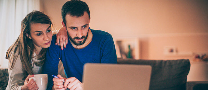 couple looking concerned sitting in front of laptop