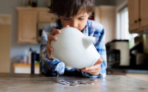 Money for kids, boy emptying piggy bank.