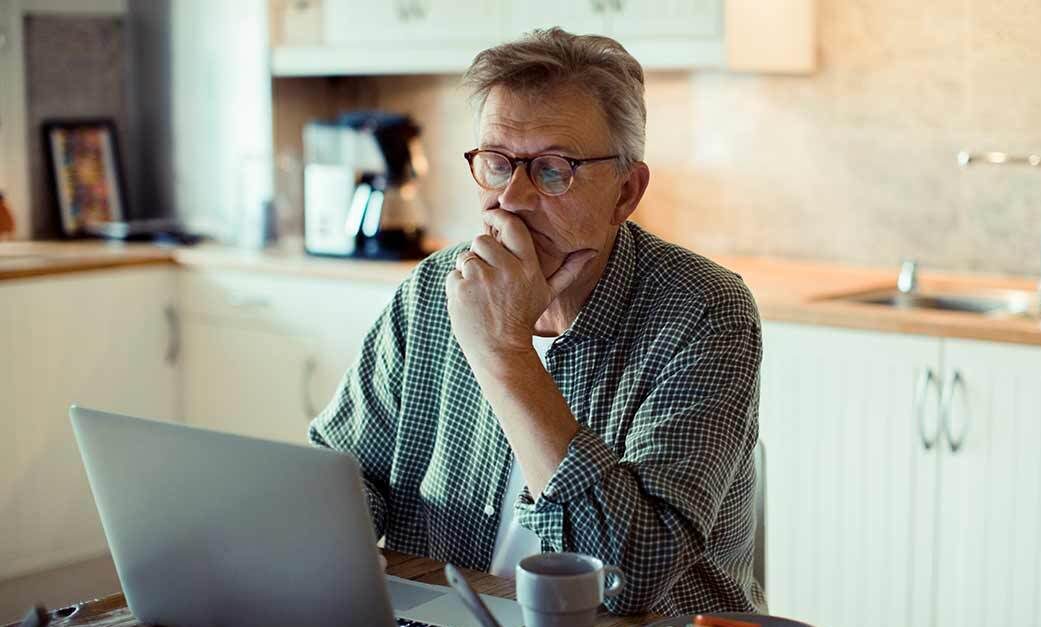 Man sitting in front of laptop considering different options