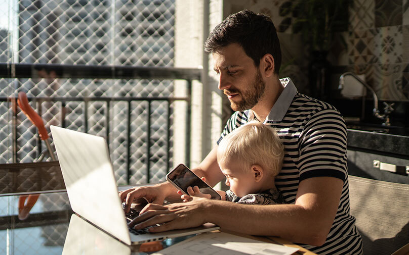 Man with baby on computer looking at factors that affect his credit.