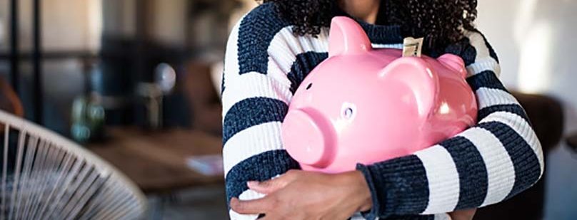 young woman hugging her pink piggy bank