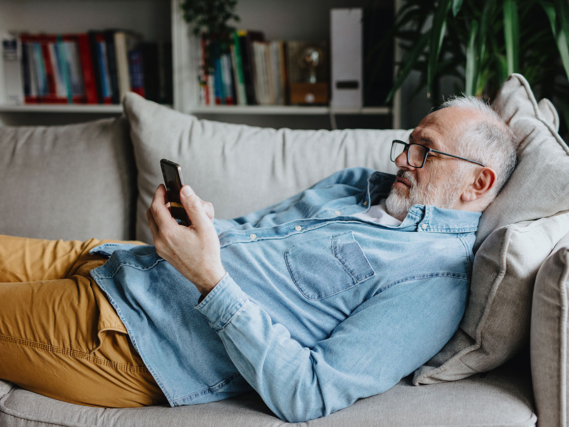 Man laying on the couch looking at his phone