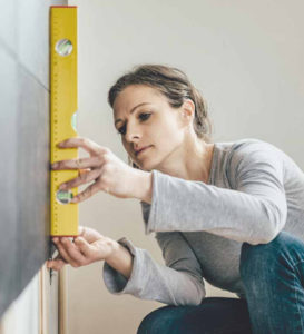 Woman balancing and measuring a wall