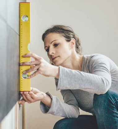 Woman balancing and measuring a wall