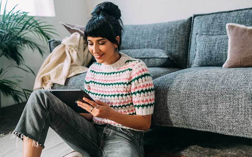 Woman sitting on the floor smiling at her phone