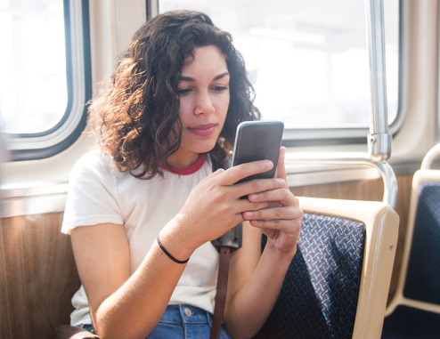 Woman on the bus sitting down looking at her phone