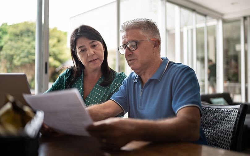 Mature couple looking through paperwork in front of computer