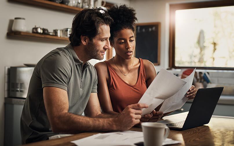 Couple looking at paperwork in front of laptop
