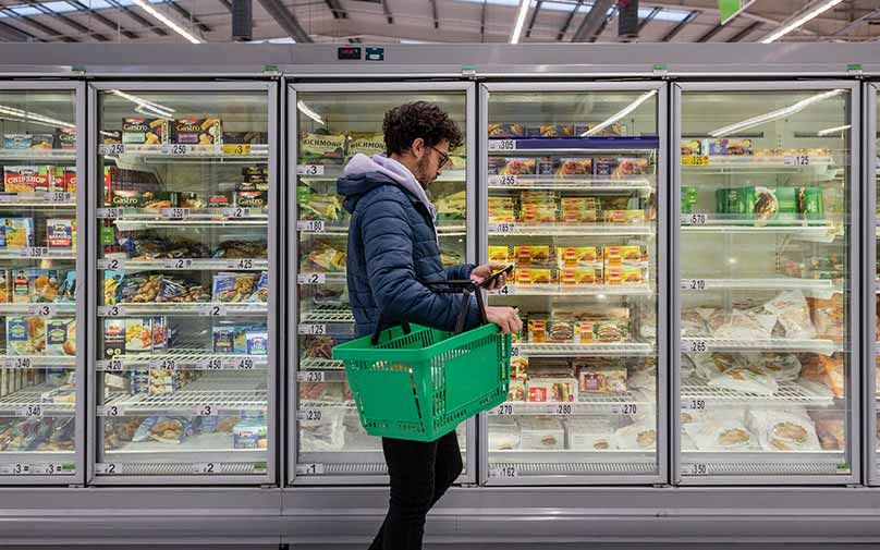 man at grocery store learning to cut expenses