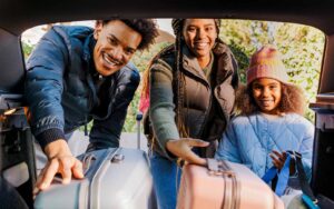 Family putting luggage in car for holiday travel
