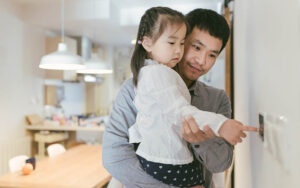 Father and daughter use thermostat to lower temperature