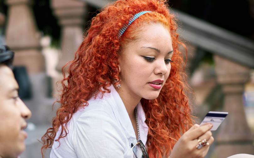 Woman sitting on step looks at her credit card