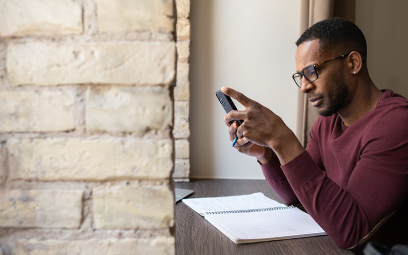 Man looking at phone while making financial plan