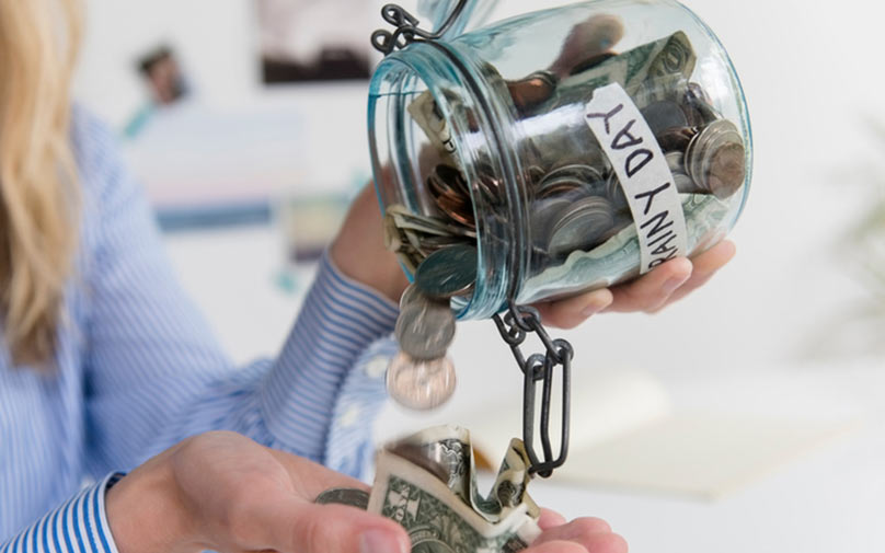 Pouring coins out of rainy day fund jar