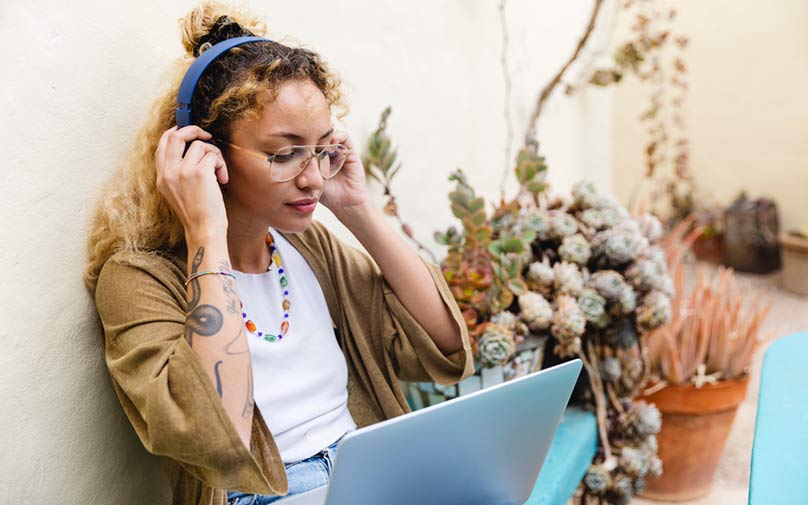 Woman wearing headphones listening to podcast on laptop