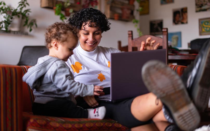Mother sitting with toddler while on computer