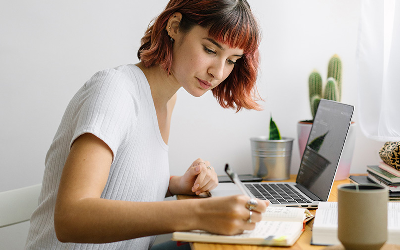 Woman writing the differences of soft vs. hard credit checks