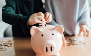 Children putting money in a piggy bank