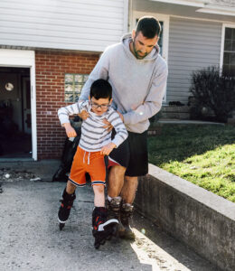 Man helps son learn to rollerblade