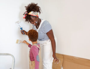 Mother and child painting white wall together during home renovation project