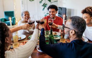 Celebrate Thanksgiving on a Budget - Family cheering with wine over dinner.