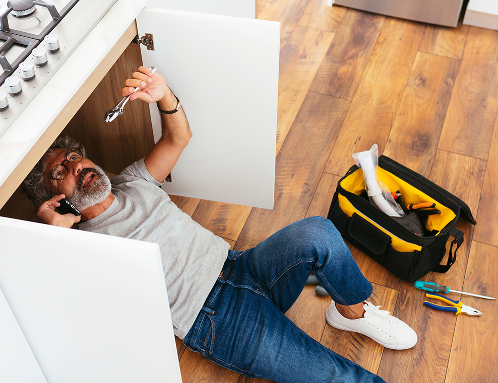 Handyman installing kitchen cabinet hardware with tools on hardwood floor