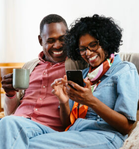 Couple happily drinking coffee and looking at phone