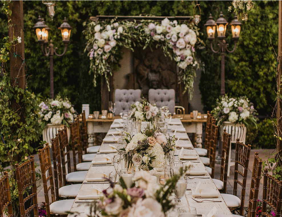 Elegant outdoor wedding reception table with white flowers and candlelit lanterns
