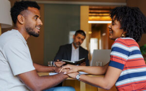 Couples happily discussing combining finances in office