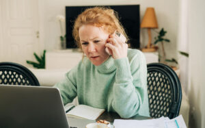 Woman finding out what to do because she has been scammed using phone and laptop