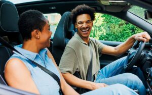 Two people sitting in a car after deciding to refinance with a car loan to raise credit score