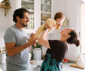 Parents smiling and playing with baby in kitchen at home